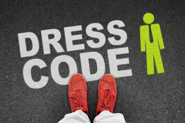 Ein Mann in auffälligen, roten Schuhen steht vor einem Schriftzug. Der Schriftzug lautet Dresscode.