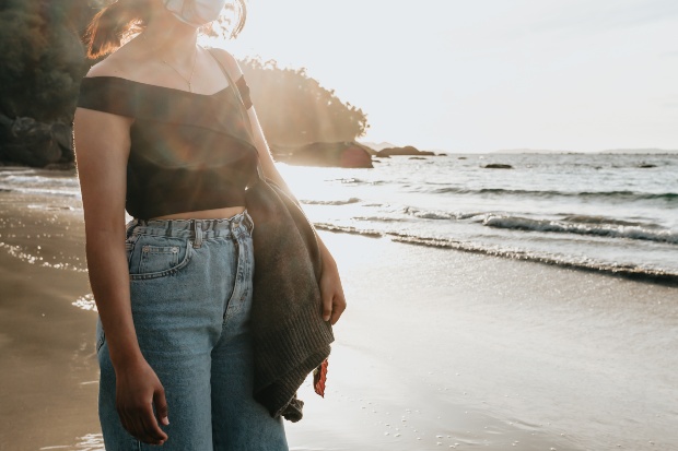 Junge Frau in Mom Jeans am Strand - Mom Jeans kombinieren zum Beispiel mit einem schwarzen Top