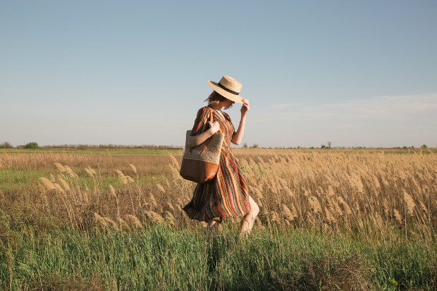 Eine Frau im Wickelkleid läuft über ein sommerliches Feld Sanduhr-Figur