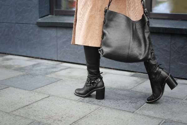 Eine Frau mit Mantel und Stiefeln schreitet eine Passage entlang Winteroutfits für Damen