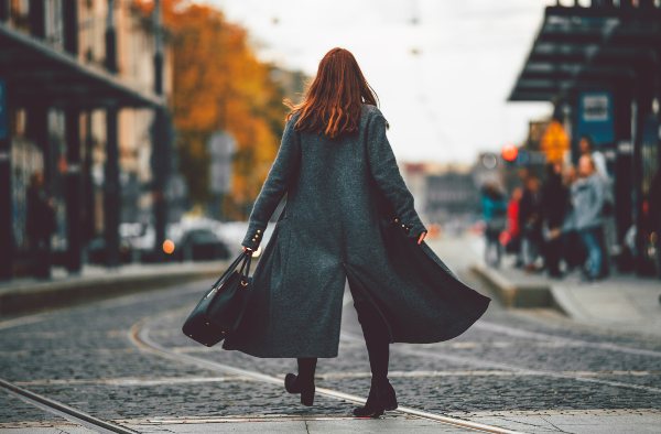 Eine Frau im langen Wollmantel vor urbaner Kulisse Winteroutfits für Damen