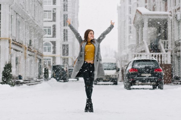 Eine Frau steht im Schnee vor urbaner Kulisse
