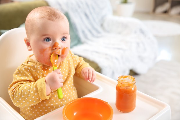 Baby löffelt Breit, ist bekleckert - die Erstausstattung fürs Baby muss oft gewaschen werden