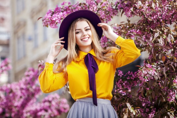 Junge Frau mit gelber Bluse und violetter Krawatte und Hut - Komplementärfarben in der Mode