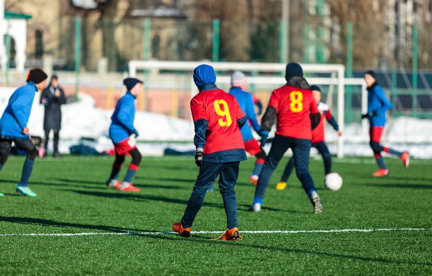 Kinder spielen Fußball im Winter