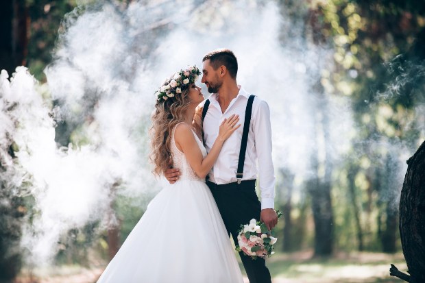 Junges Brautpaar steht vo einer Nebelkerze, die Rauch ausstößt