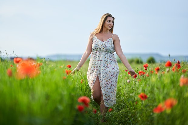 Junge Frau mit Blumenkleid in einem Mohnfeld - Kleider für kleine Frauen