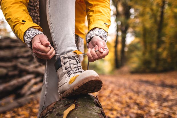 Jemand schnürt seine Wanderschuhe - Wandern im Herbst