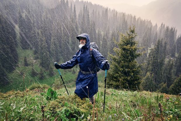 Älterer Mann beim Bergwandern bei starkem Regen - Wandern im Herbst