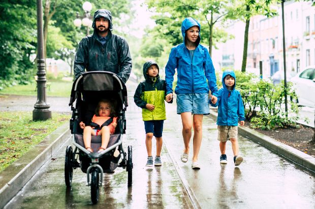 Junge Familie spaziert bei Regenwetter - Regenmode