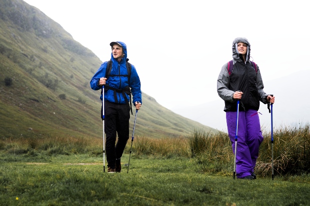 Junge Paar wandert bei nassem Wetter durch Berglandschaft