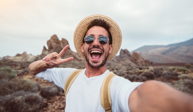 Junger Mann mit Strohhut macht Selfie