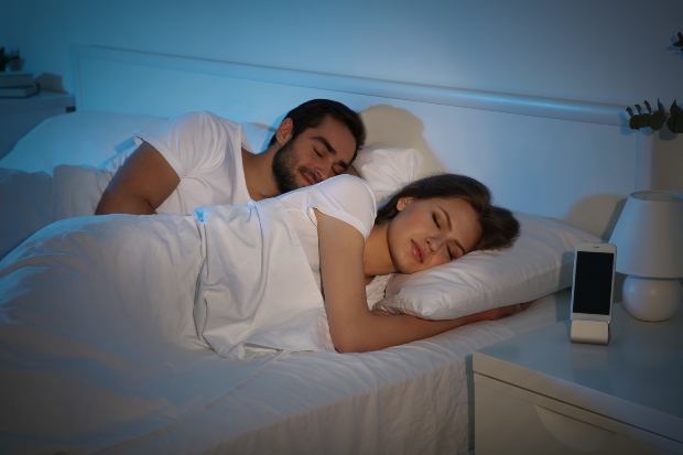 Junges Paar liegt gemeinsam im Bett und schläft - Welche Kleidung zum Schlafen?