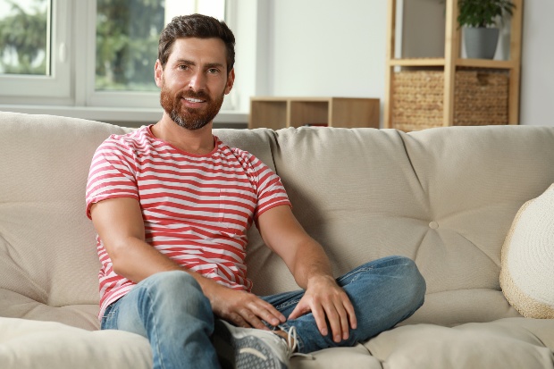 Junger Mann auf der Couch mit rot-weiß-gestreiftem T-Shirt - Streifenshirt und Streifenpullover kombinieren