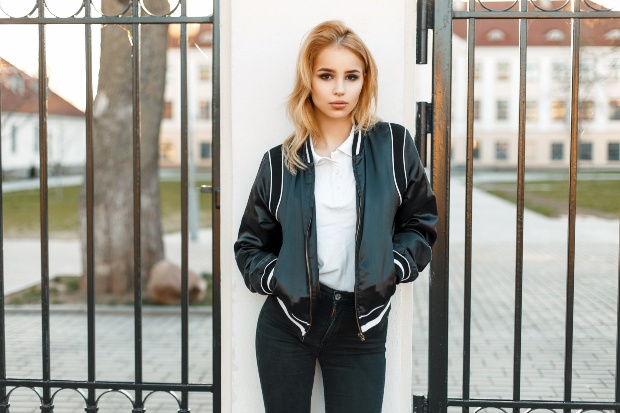 Junge Frau mit Sportjacke, Polo-Shirt und schwarzen Jeans