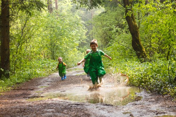 Matschhosetragende Kinder springen durch Pfützen!