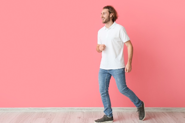 Junger Mann mit weissem Polo-Shirt und Bluejeans