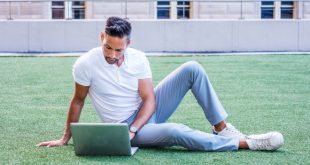 Mann-mit-weissem-Polo-Shirt-auf-Rasen-mit-Laptop - Weißes Poloshirt für Herren