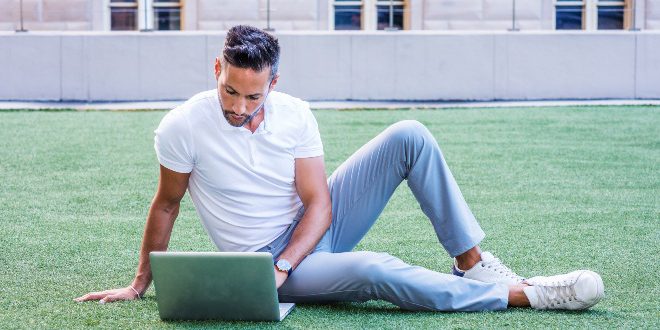 Mann-mit-weissem-Polo-Shirt-auf-Rasen-mit-Laptop - Weißes Poloshirt für Herren