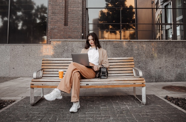 Junge-Frau-auf-Parkbank-mit-Laptop - minimalistischer Kleidungsstil