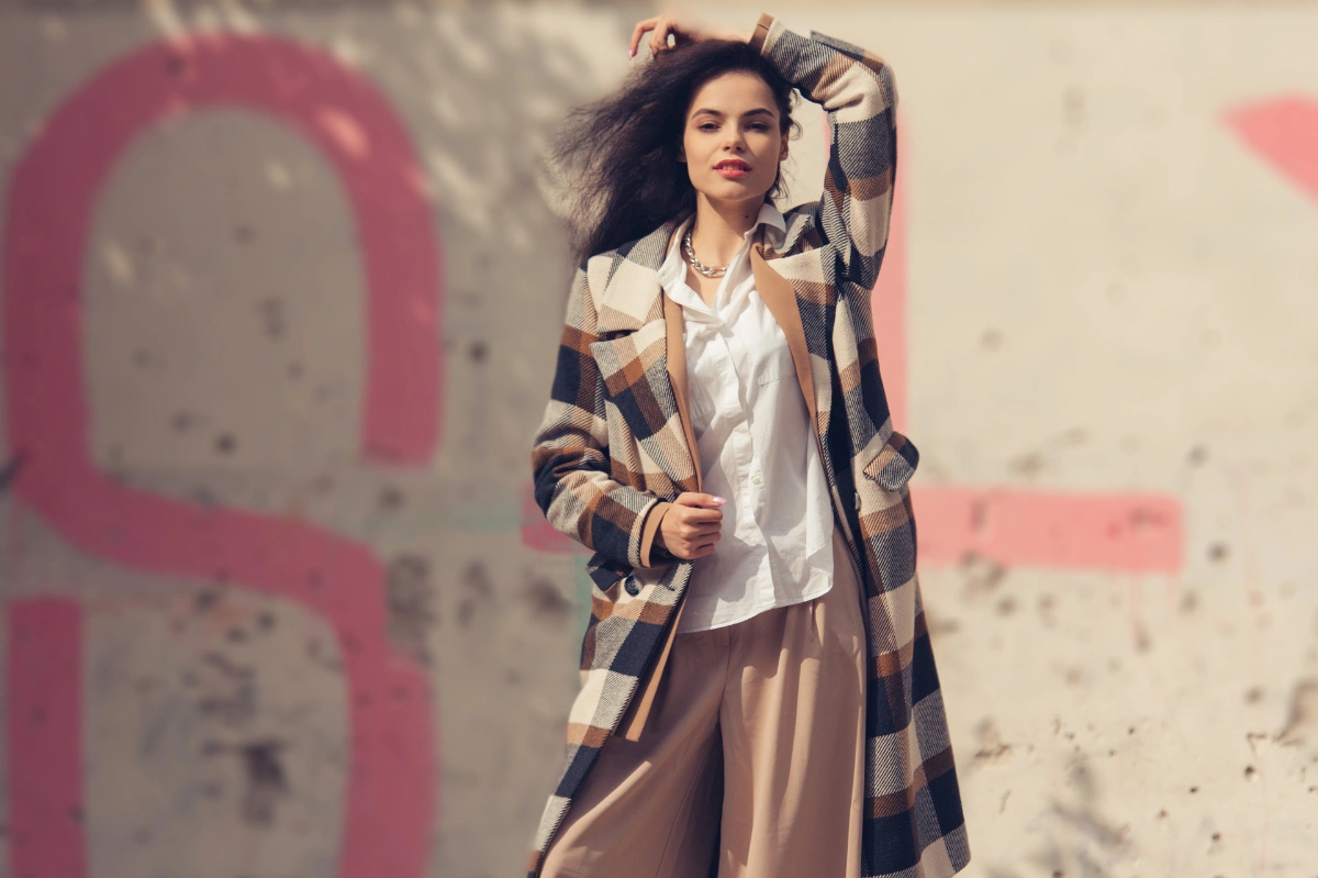 Frau kombiniert weiße Bluse, Blazer und Herbstmantel