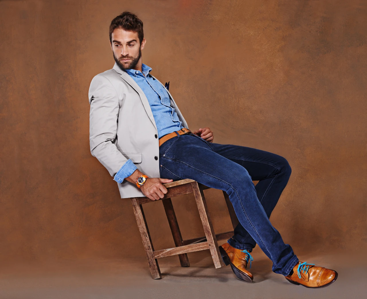 Mann kombiniert hellblaues Jeanshemd mit einem eleganten Sakko für einen formellen Anlass