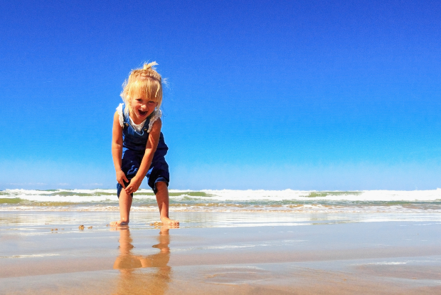 Mädchen mit blauer Latzhose am Strand